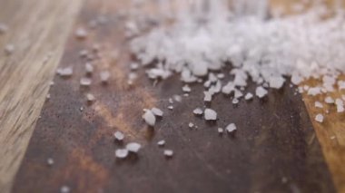 Kırsal ahşap bir yüzeye düşen spa deniz tuzu. Makro. Yavaş çekim