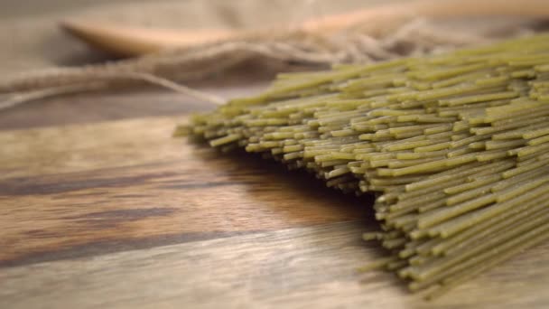 キノア粉とニンニクとパセリの粉から作られた生の有機バイオグリーンスパゲティ ざわめきのある素朴な板とぼかしの木のスプーンで 選択的フォーカス 接近中だ ドリーショット — ストック動画