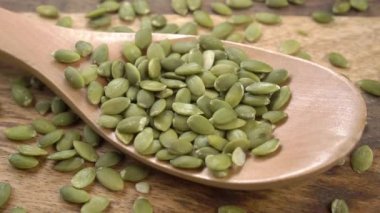 Taze yeşil balkabağı çekirdekleri yavaş çekimde kırsal bir tahta kaşığa düşer. Kapat.