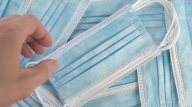 El bir yığın içinde tıbbi koruyucu cerrahi maske alıyor. Kapatın. Solunum koruması. Virüs ve toz konseptine karşı. Yavaş çekim