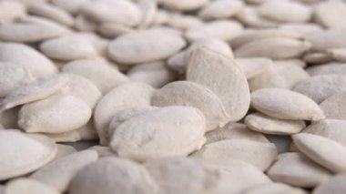 Kızarmış tuzlanmış beyaz balkabağı çekirdeği. Döndür ve ağır çekimde düş. Makro çekim