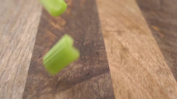 Świeże Posiekane Zielone Łodygi Selera Spadające Plasterki Rustykalnej Drewnianej Powierzchni — Wideo stockowe