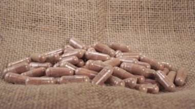 Bir el, kaba bir kırsal çuval bezinde tıbbi kahverengi bitkisel kapsülleri alır. Kapatın. Eczane hapları