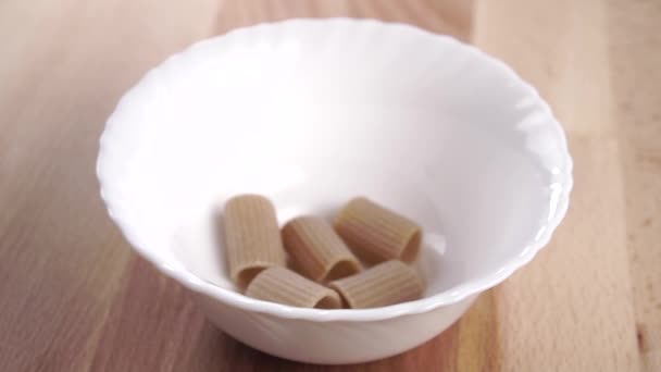 Droge Ongekookte Bruine Integrale Rigatoni Pasta Vult Een Witte Keukenkom — Stockvideo