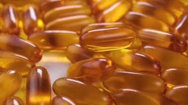 Omega 3 kapsülleri. Sarı turuncu destek hapları yavaş çekimde düşüyor. Makro atış. Vahşi somon yağı içeriyor. Döndürme