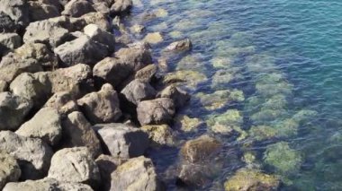 Sakin sörf ve taşlarla huzurlu bir deniz kıyısı. Ağır çekim. Güzel deniz kıyısı