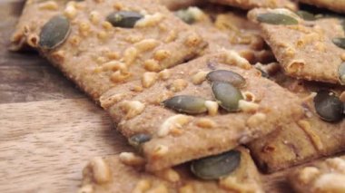 Tahta bir masada, kabak tohumları ve emmental peynirle çıtır çıtır çavdar ekmeği. Makro. Dolly vurdu. Desenli yüzey