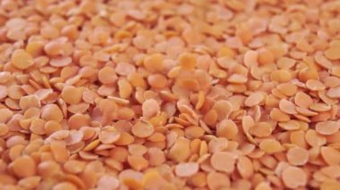 Portakallı kuru pişmemiş mercimek. Makro. Çiğ Kızılderili baklagilleri ağır çekimde yığının içine düşüyor. Döndürme