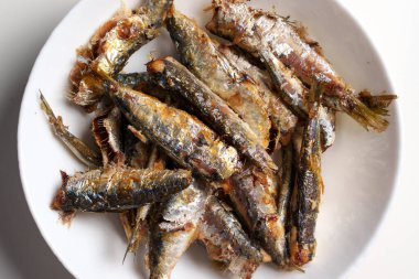 Fried sardine fish on a white kitchen plate. Top view
