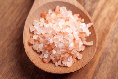 Ahşap bir kaşıkta portakal ve beyaz kristaller bulunan kaba besleyici Himalaya tuzu