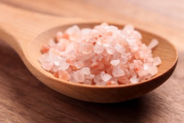 Kaba Himalaya tuzu ve portakal kristalleri ahşap kırsal kaşıkta. Yaklaş.