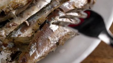 Mutfak çatalı tabakta kızarmış sardalyayı delip geçiyor.