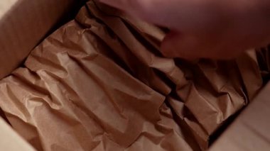 El, karton bir kutudan buruşuk kağıt, yumuşak dolgu malzemesi çıkarır.