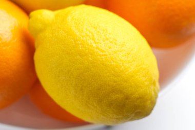 Turunçgil yığını içinde taze sarı limon. Beyaz bir masada portakallar.