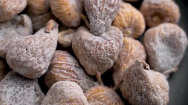 Siyah seramik bir yüzeye pudra şekerle kaplı kuru incirler.