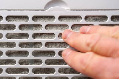 İnsan parmaklarının dokunduğu tozlu hava temizleme filtresi. Alerji bileşeni. Ev bakımı kavramı