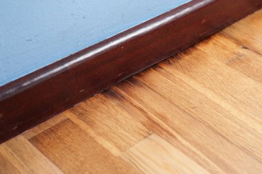 Mavi bir duvarın yanında hasarlı kaplama döşeme ve oturma odasındaki nem yüzünden ahşap süpürgelik. Maddi bozulmaya bağlı nem etkisi