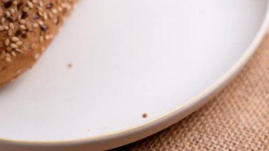 El, seramik tabağa gevrek bir Fransız ekmeği koyar..