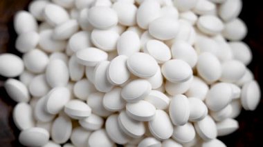 Ahşap kasede beyaz ilaç tabletleri yığını. Doğal destek hapları. Sağlık desteği kavramı. Üst görünüm