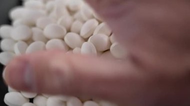 İnsan eli bir avuç dolusu beyaz oval ağrı kesici alıyor. Ağrı kesici ve ilaç tedavisi kavramı