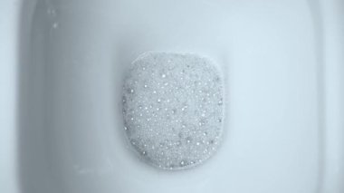 Su yüzeyinde köpükle dezenfekte edilmiş temiz klozet.