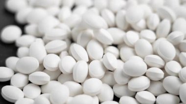 İlaç beyaz haplar yavaş çekimde büyüyen bir yığın hapın üzerine düşüyor. Kapat.