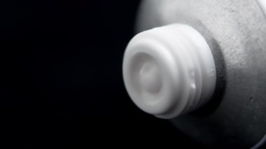 Beyaz kozmetik kremi siyah arka planda bir tüpten sıkılıyor. Makro çekim