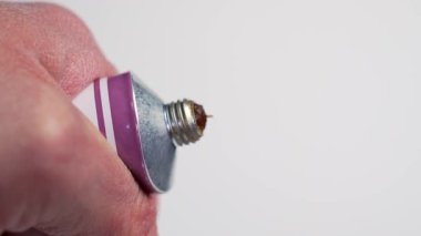 Beyaz arka planda kediler için bir tüp vitamin macunu sıkan bir elin yakınına. Hayvan bakımı ve tüy kontrolü kavramı