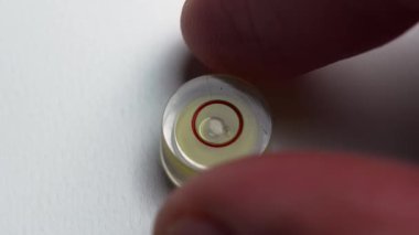 Yüzey düzlüğünü kontrol ettikten sonra parmaklar yuvarlak bir kabarcık seviyesini kenara çekiyor. Hassas ölçüm aracı. Hizalama doğrulama ve kalite kontrol kavramı