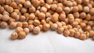 Bej kumaşın üzerine yavaş çekimde düşen nohutlar.