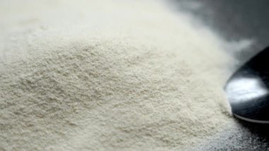 Metal kaşık siyah arkaplandaki bir yığından kaliteli kolajen protein karışımı topluyor. Besleyici konsantrasyon. Sağlıklı yaşam tarzı ve iyileşme kavramı