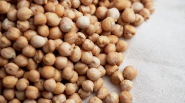 Pişmemiş nohutlar doğal keten kumaşlara saçılmış. Bej, kurutulmuş baklagiller. Bitki temelli protein beslenme konsepti