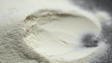 Protein tozu paslanmaz çelik bir kaşıkta besin spor malzemesi yığınına yerleştiriliyor. Fitness beslenme ürününün yavaş çekim makrosu.