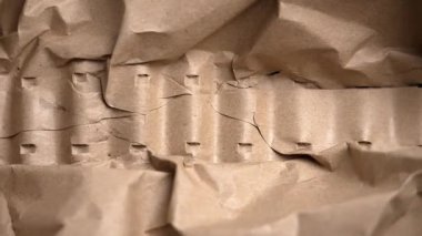 Eller buruşmuş kraft kağıdını sıkıştırıyor ve açıyor. Yumuşaklıkla esneklik gösteriyor. Kahverengi paketleme malzemesi basınç altında şekil değiştiriyor. Koruyucu ambalaj kavramı
