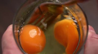 Cam bardakta iki çiğ tavuk yumurtası çırpıyorum. Ev yemeği hazırlama sırasında sarıları ve beyazları karıştırmak