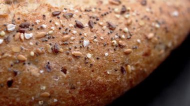 Keten, susam ve haşhaş da dahil olmak üzere karışık tohumlarla kaplı fırında ekmek kabuğu. Siyah arkaplanda Rustik fırın ürünü