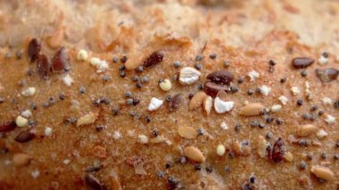 Besleyici zengin tohumlar ve tahıllarla kaplı tam tahıllı ekmek yüzeyi. Doğal gıda dokusu ve sağlıklı pişirme konsepti. Makro atış. Döndürme