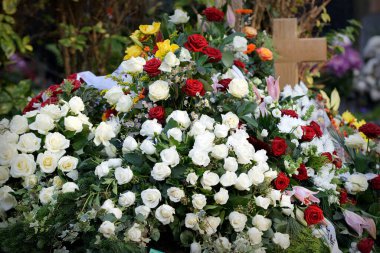 many flowers after a funeral on a grave with a wooden cross clipart