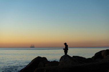 Dalgakıranda gün doğumunda balıkçı silueti