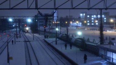 Tren raylarda giderken istasyonda yürüyen insanlar