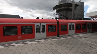 Metro istasyonunda hareket eden kırmızı trenli insanlar.