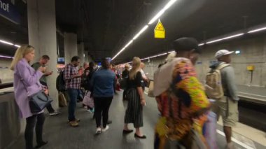 Metro istasyonunda hareket eden kırmızı trenli insanlar.