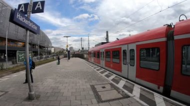 Metro istasyonunda hareket eden kırmızı trenli insanlar.