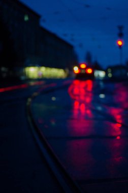 Aydınlatılmış ıslak asfalt üzerindeki tramvay raylarının görüntüsü