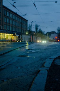 Aydınlatılmış ıslak asfalt üzerindeki tramvay raylarının görüntüsü