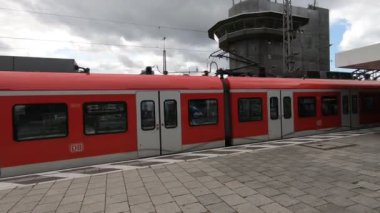 Metro istasyonunda hareket eden kırmızı trenli insanlar.