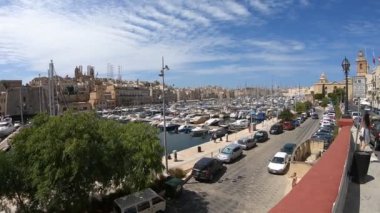 Limandaki tekneler, park halindeki arabalar ve güneş sokakta yürüyen insanlarla dolu binaları aydınlattı.