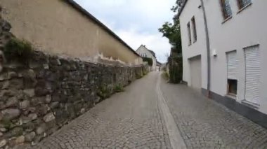Hareket halindeki arabaları ve insanları olan eski şehir sokaklarında yürüyen insanlar.
