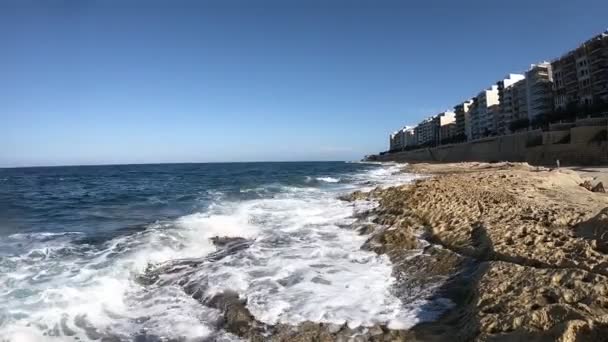 Golven Rollen Rotsachtige Kust Met Gebouwen Fel Zonlicht Met Blauwe — Stockvideo