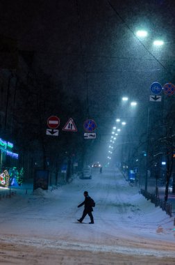 Karlı Kyiv Caddesi 'nden geçen adam gece aydınlandı.